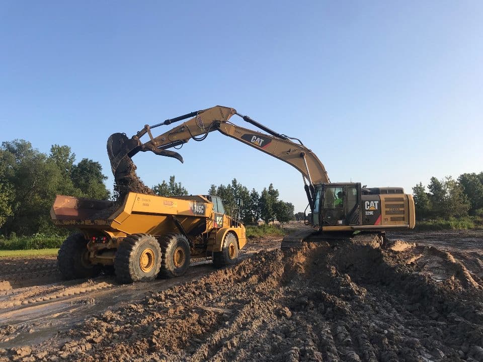 Equipment moving dirt to build a dam