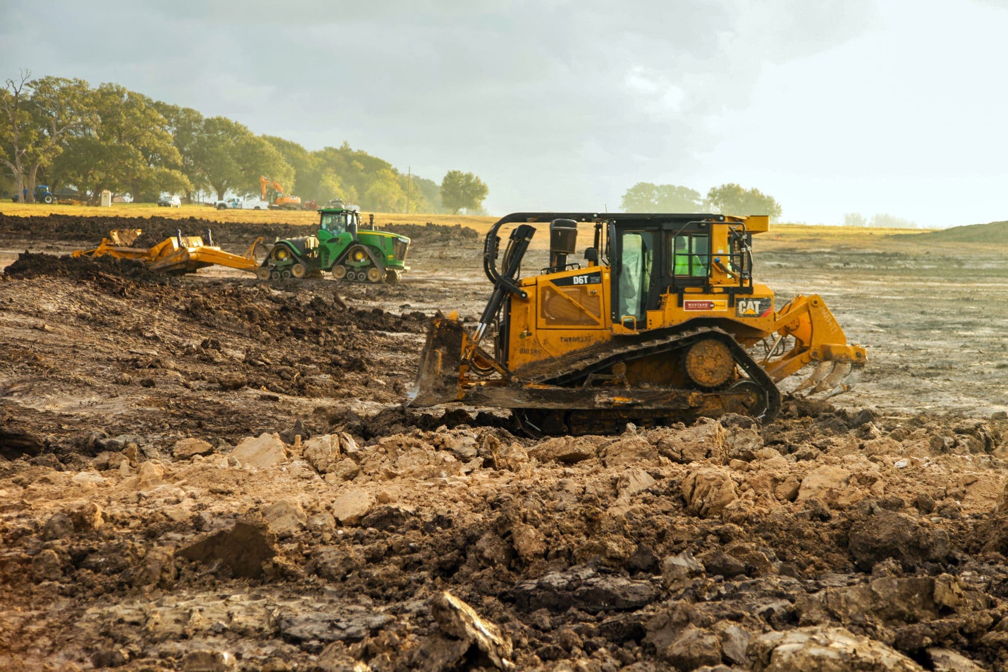 Heavy equipment moving earth to build a pond dam