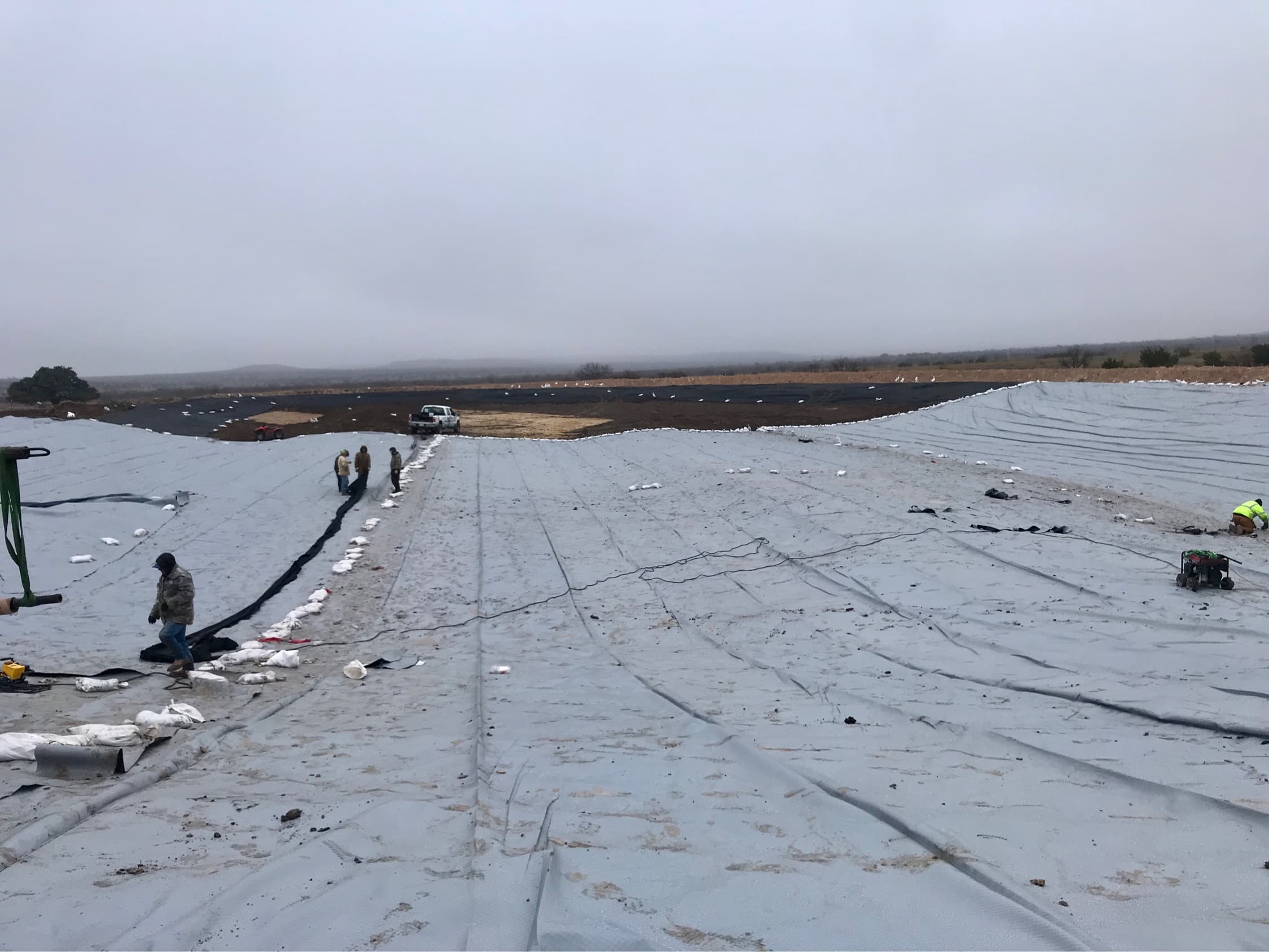 Crew installing a liner across a pond bed