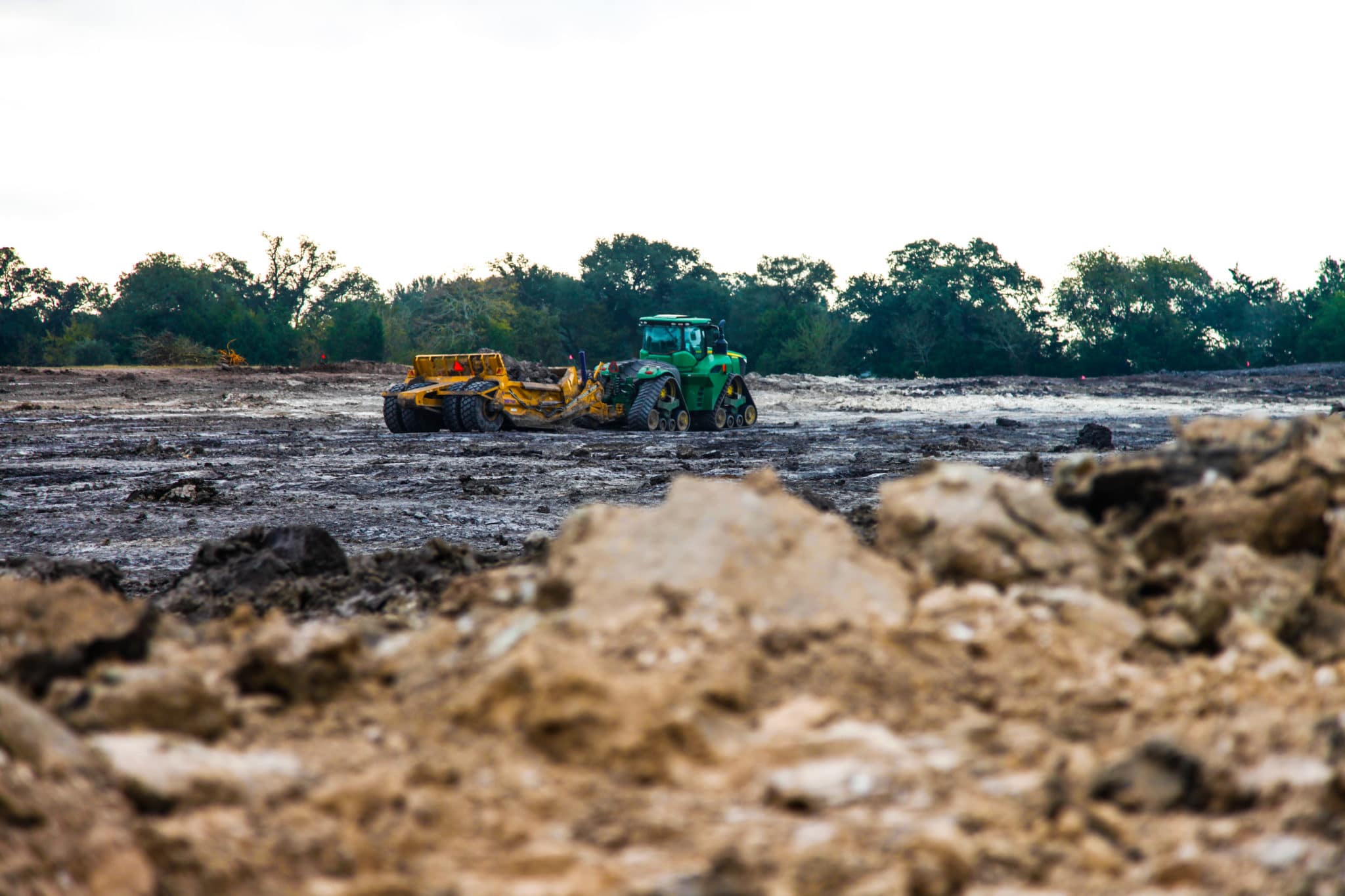 A tractor shaping a new pond basin beside filling water
